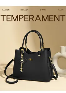 Detail of black leather handbag with golden kangaroo logo and heart tassel charm accessory