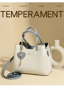 Detail of elegant two-tone leather handbag with golden kangaroo logo and heart charm