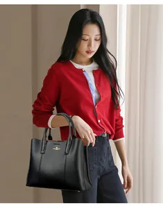 Détail d'un sac cabas en cuir noir avec logo kangourou doré pour un style de bureau