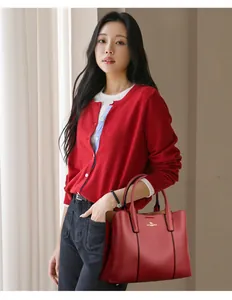 Détail du sac à main rouge en cuir grainé avec logo kangourou doré sur mannequin