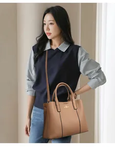 Sac fourre-tout en cuir marron avec logo doré porté par un mannequin pour le quotidien