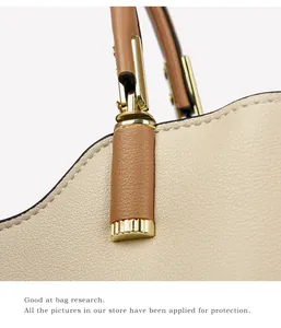 Macro detail of beige pebbled leather tote with tan handle and gold metal fastener