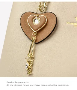 Detail of lychee textured leather bag with heart pendant and gold LOVE charm