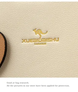 Macro shot of cream pebble leather texture and gold kangaroo logo on elegant handbag