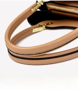Close-up of camel leather handbag featuring gold-tone hardware and round handle details