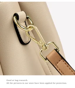 Detail of lychee pattern leather and light gold metal hook on the beige crossbody bag
