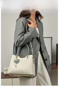 Detail of grey-blue leather handbag featuring gold heart charm and kangaroo emblem
