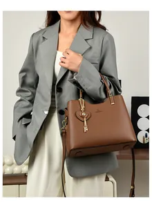 Brown faux leather handbag featuring a golden heart pendant and shoulder strap detail