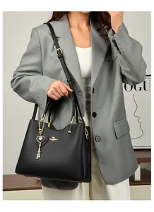 Close-up of black leather handbag with gold kangaroo logo and heart charm detail