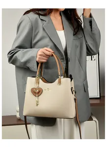 Detail of a creamy white leather handbag with gold kangaroo logo and heart charm detail