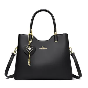 Black leather handbag with gold kangaroo logo and heart charm on a white background