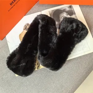 Detail of plush black faux mink scarf texture with elegant orange brand packaging