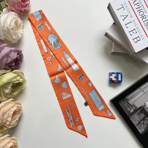 Foulard twilly étroit 90cm orange avec des illustrations de plumes et de papeterie dessinées