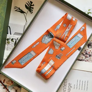 Écharpe Twilly en soie orange aux motifs de bureau dans un élégant coffret cadeau vert