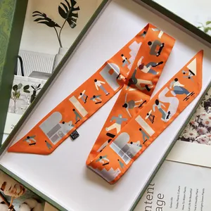Vue macro d'un foulard en soie orange avec lettrage Paris dans un coffret de luxe vert