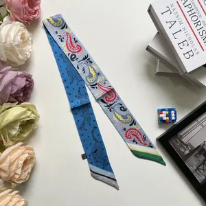 Close-up of dual-sided paisley and leopard print silk-like scarf tied on a white bag handle