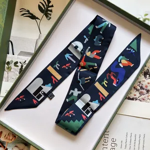Détail d'un foulard en soie avec illustration de ski dans une boîte cadeau verte