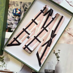 Pink satin twilly scarf with black and white geometric pattern in a green gift box