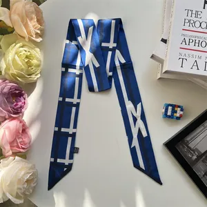 Close-up of royal blue silk twilly scarf with geometric patterns on an open book