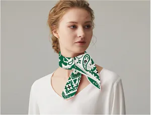 Detail of silk-like paisley square scarf in green and white tied around the neck gracefully