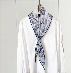 Detailed view of Toile de Jouy silk twilly scarf with blue nature print on white shirt