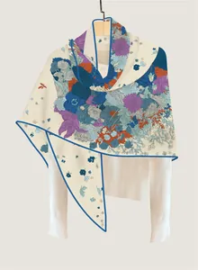 Detail of floral cashmere-like scarf with blue contrast borders and artistic prints