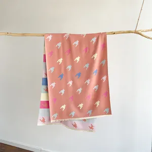 Detail eines korallenrosa Strickschals mit Hahnentrittmuster und feinen Fransen