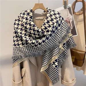 Close-up of houndstooth scarf with fringe detail draped over a wool coat for winter fashion