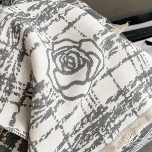 Detail of rose floral pattern and tassel edges on a soft grey knit winter shawl