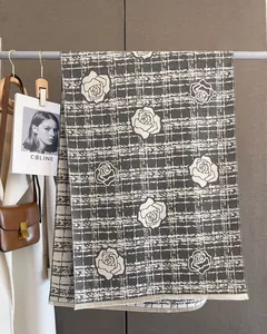 Close-up of elegant rose flower pattern on black and white plaid wool scarf with fringes