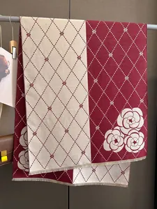 Detail of camellia floral knit patterns and fringe on beige and burgundy scarf