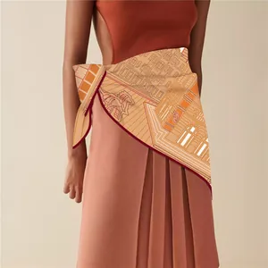 Detail of orange silk scarf with classical horse carriage print worn as a chic waist belt