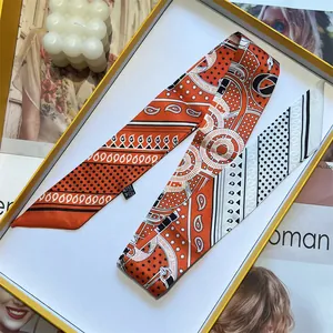 Close-up of a folded silk twilly scarf with paisley and star patterns in a gold gift box