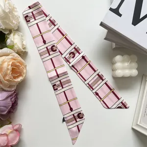 Detailansicht eines rosa Seidenschals mit Karomuster, Gürtelschnallen und Etikett