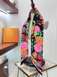 Détail d'un foulard en soie noir avec des motifs floraux rose et orange sur un mannequin