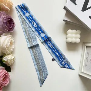 Détail d'un foulard Twilly étroit avec motif chaîne bleu et étiquette d'entretien