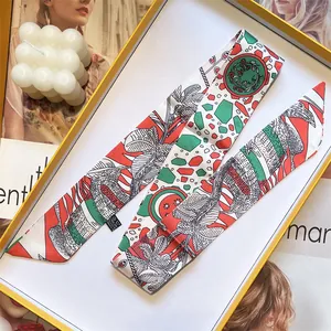 Makroaufnahme eines Twilly-Seidenschals mit tropischem Print in einer Geschenkbox