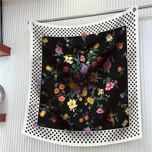 Détail d'un foulard en soie à fleurs avec bord à pois et étiquette de marque dorée