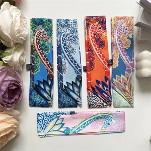 Detailed flat lay of polyester twilly scarves with giraffe and lotus floral patterns