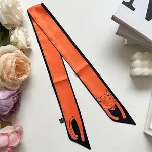 Détail d'un foulard Twilly orange en soie avec chat de dessin animé pour sac à main