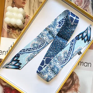 Macro view of blue patterned narrow silk scarf displayed in elegant gift box