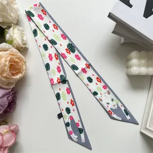 Détail d'un foulard en soie avec imprimé floral et chat à côté de bougies et fleurs