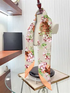 Detailopname van een zijden twilly sjaal met bloemenprint en oranje rand op een mannequin
