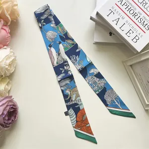 Detail van zijden sjaal met pinguïn- en bloemenprints naast rozen en boeken