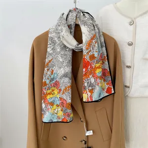 Artistic floral print silk wool narrow scarf draped on a brown wool coat stylish design