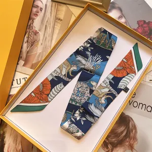 Detailopname van de luxe zijden twilly sjaal met bloemenprint in oranje geschenkdoos
