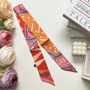 Detailed view of an orange and red geometric silk twilly scarf for DIY handbag decoration