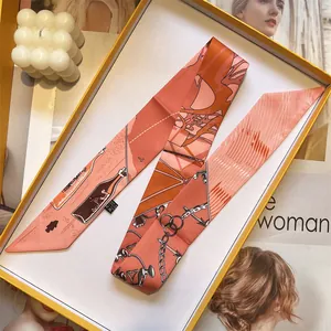 Elegant silk twilly scarf with chain pattern in orange box with lifestyle decor