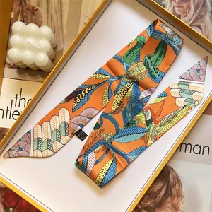 Pañuelo twilly de seda naranja con estampado floral y aves tropicales en caja de regalo