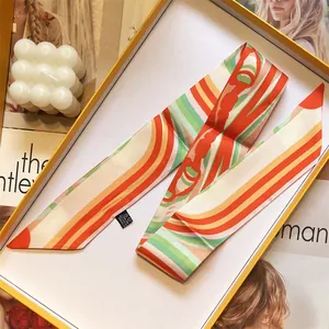 Elegant orange silk twilly scarf with geometric patterns in a luxury gift box